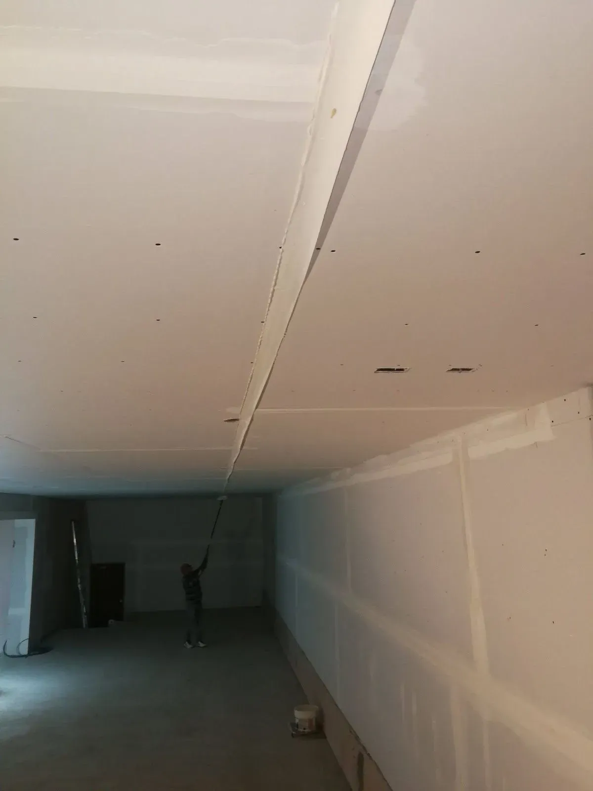 Freshly hung drywall along a corridor, seams taped and ready to finish